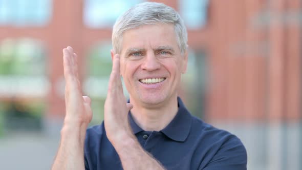 Outdoor Portrait of Successful Middle Aged Man Clapping with Hands