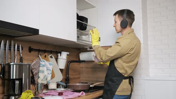 Man Washes Dishes Dancing and Listening Music in Headphones