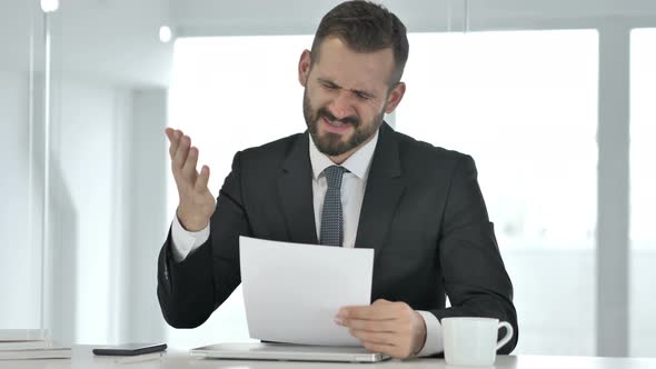 Angry Businessman Reacting To Loss While Reading Documents