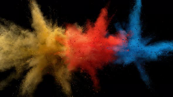 Colorful powder/particles fly after being exploded against black background. Slow Motion.