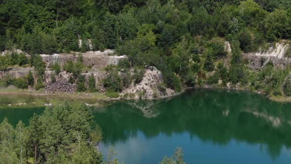 Aerial View of Beautiful Lake With Small Island and Blue Water Enclosed by Rocky Cliffs Tracking Bac