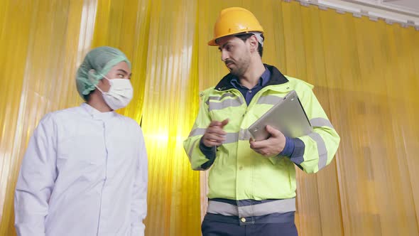 Asian male supervisor and caucasian manager inspecting bottle of herb drink