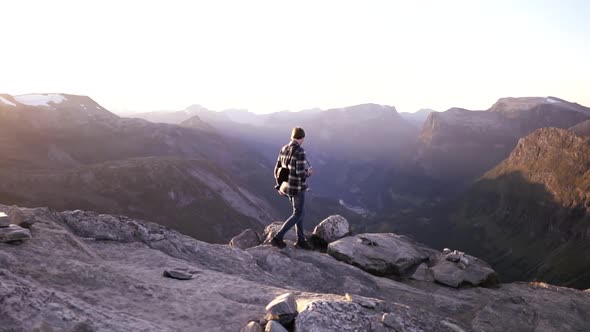 Man walking at the peak of a mountain at sunset in slow motion, Norway, Europe.