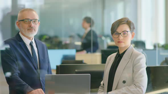 Portrait of Senior Businessman and Young Woman in Office