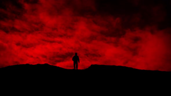 Man Approaches Over Hill On Red Sky Silhouette