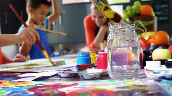 Teacher assisting schoolkid in drawing class