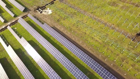 Aerial view of solar power plant under construction on green field. Assembling of electric