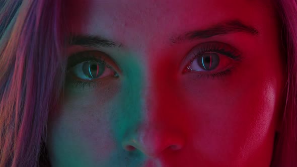 Womens Eyes with Neat Natural Makeup, Illuminated with Colorful Neon Light, Look Straight Ahead