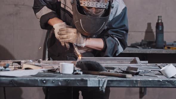 Young Man Worker in Protective Gloves and Helmet Welding Parts of the Metal Detail Together