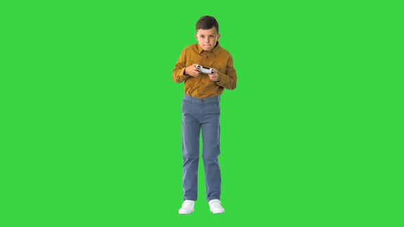 Emotional Little Boy Playing Video Games with Joystick in His Hands on a Green Screen Chroma Key
