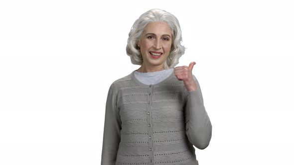 Smiling Senior Woman Pointing Thumb Behind Her Back