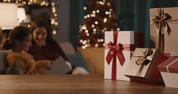 Happy mother and daughter spending time together during holidays, Christmas gifts in the foreground