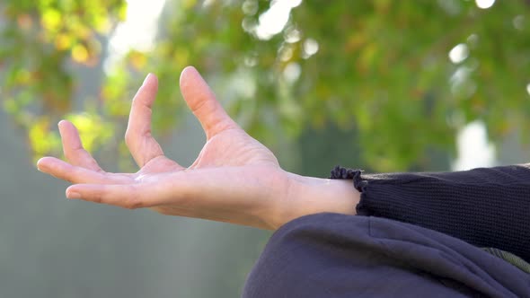 Woman practicing yoga places her hand in position slowly and then opens it