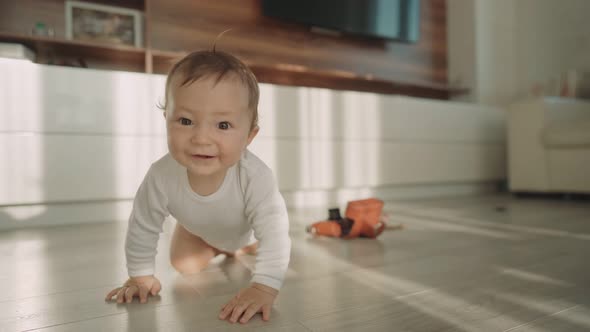 Cute Happy Little Toddler Baby Boy is Crawling on a Wooden Floor at Home