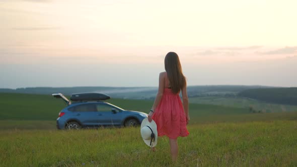 Young Woman Walking Alone on Green Field During Road Trip in Summer