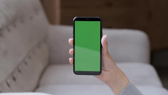 Isolated woman hands holding vertical smartphone with green mock up screen. Business woman browsing