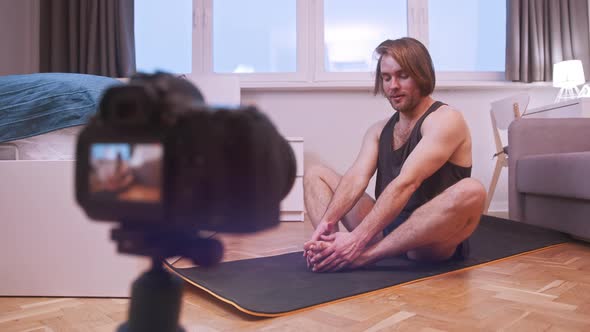 Young Man Stretching and Streaming Exercise Class