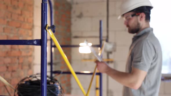 A handyman builder in a helmet is studying a construction plan.