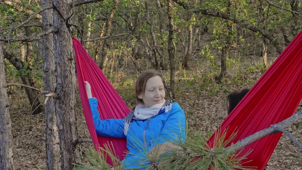 Two Friends Laugh and Talk While Lying on a Hammock in the Middle of the Forest The Idea of a