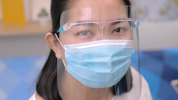 Portrait of an Asia young female who is wearing a face shield with mask rounded around her face from