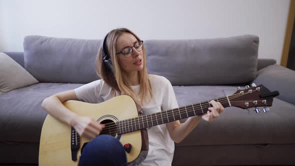 Woman in Headphones Plays the Guitar at Her Home Happily Having Fun Playing Guitar and Singing