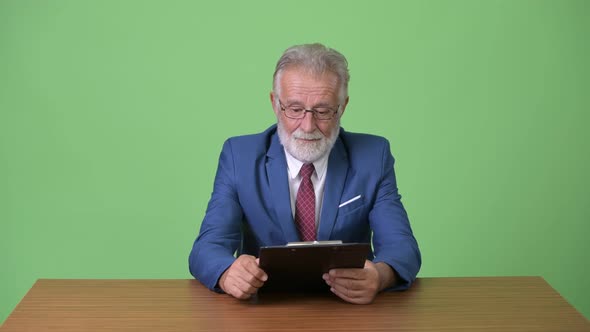 Handsome Senior Bearded Businessman Against Green Background