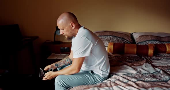 Man Sitting on Bed Looking at Empty Wallet. Male Very Dissapointed and Depressed Feelling Hopeless