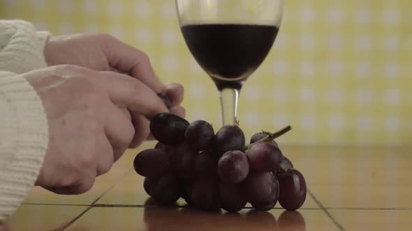 Hands holding glass of red wine eating grapes medium shot