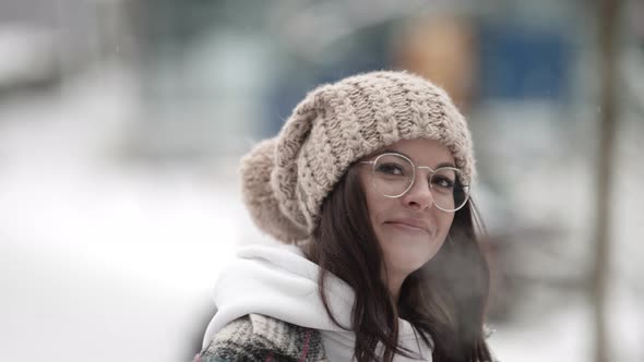 Portrait of a Happy Young Darkhaired Woman in Round Glasses and a Plaid Coat Walking on a Frosty