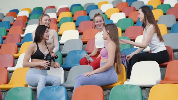 Group of Five Different Sporty Girl Sitting on Stadium Seats and Talking