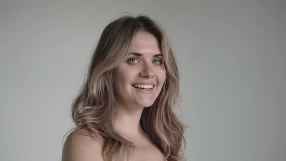 Blonde Woman Looks at the Camera and Smilingon a White Background