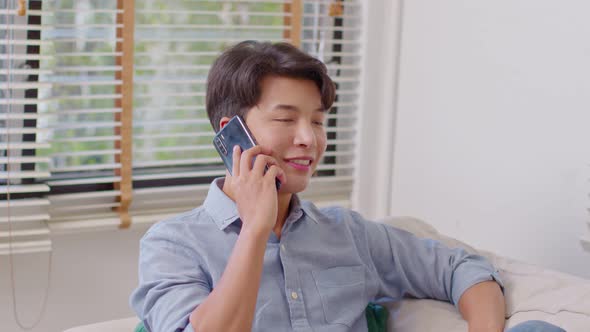 Happiness handsome asian young man smiling talking with girlfriend on mobile phone at home