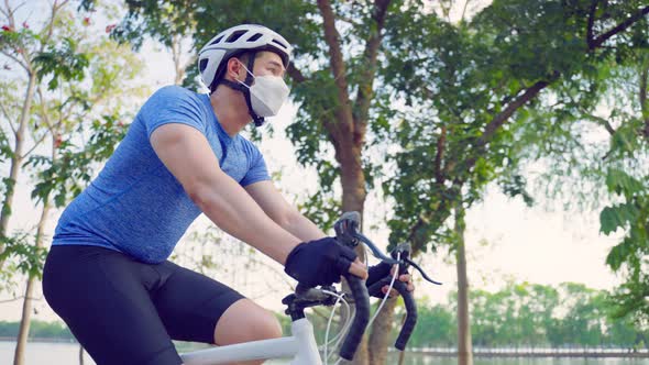 Asian young sport male wear face mask and ride bicycle in public park.