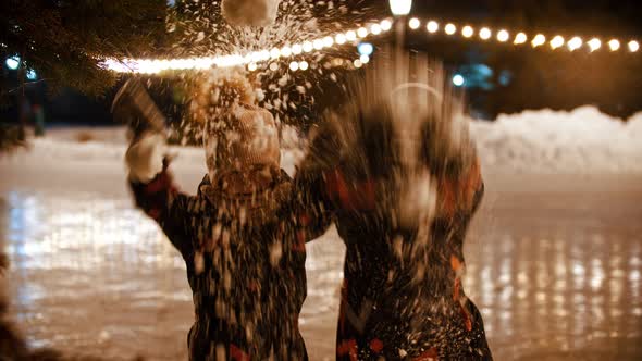 Two Little Kids Standing on Public Ice Rink and Throwing Snow in the Air