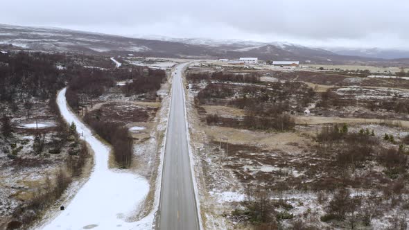 Vehicles Driving At Wintery Road With Snowy Track In Dovre, Innlandet County, Norway. - aerial