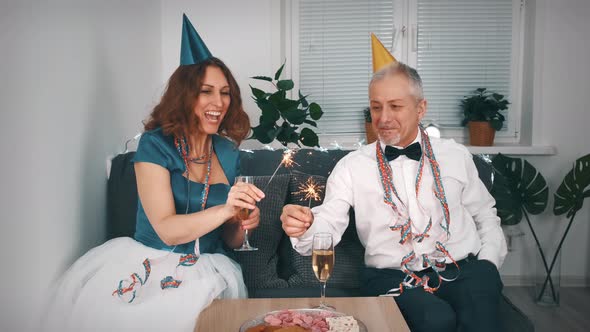 A Happy Middleaged Couple in Festive Outfits with Sparklers in Their Hands Meets the New Year's