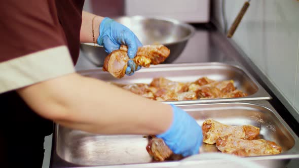 Close-up. Cuisine Worker, in Protective Gloves, Lays Out Raw Chicken Legs in Baking Sheet for