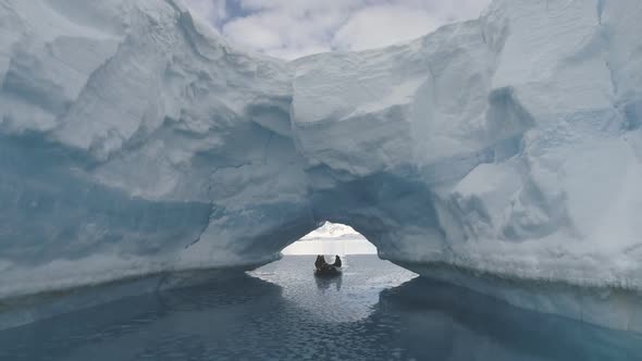 Boat Passes Through Iceberg Arch. Antarctica