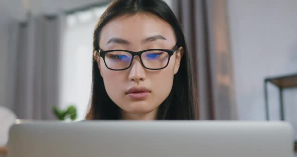 Young Oriental Appearance Girl in Glasses Working at Home Over Her Startup Project