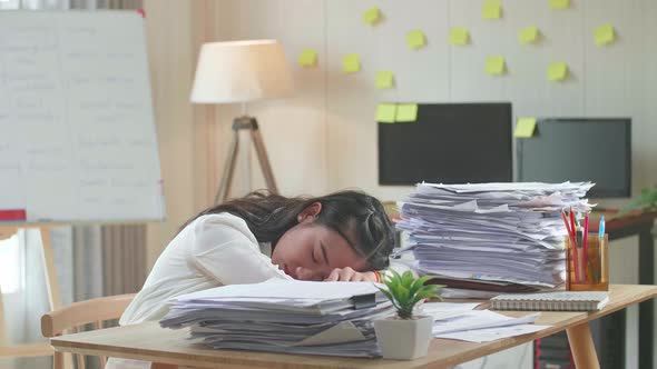 Tired Asian Woman Sleeping Due To Working Hard With Documents At The Office