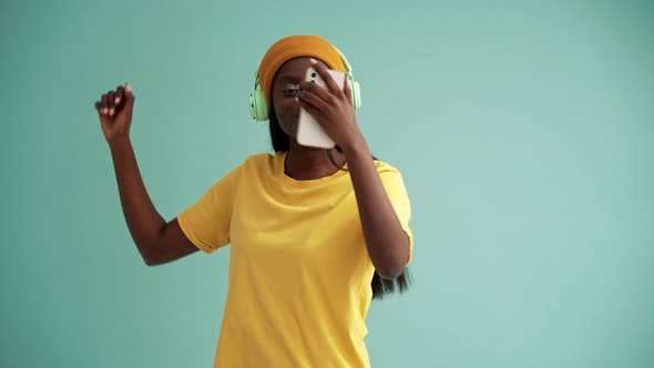 Rejoicing African woman wearing headphones dancing