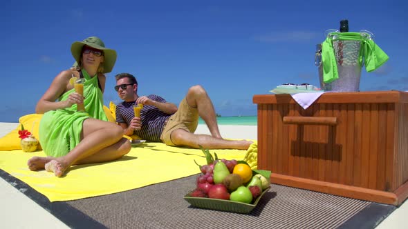 A man and woman have a picnic on a tropical island beach