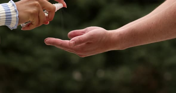 Woman disinfecting hands of her friend.