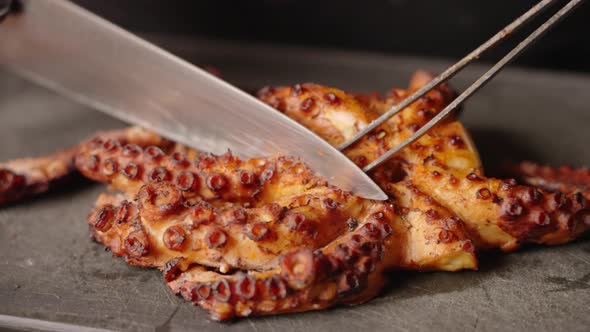 Close up shot of professional chef slicing and cutting the tentacles of perfectly grilled tender and