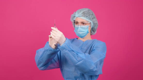 Professional Female Doctor Holds a Syringe with a Vaccine on a Pink Background