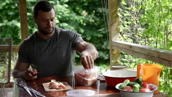 Man is Cutting Marinated Meat for Cooking on Grill Putting Pieces on Skewers