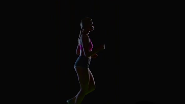 Female Athlete Runs Beautifully in a Half Turn on a Black Background. Silhouette. Slow Motion