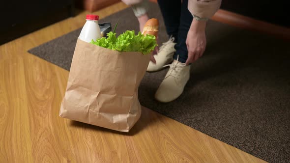 A bag of food falls when a woman places it on the floor