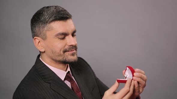 Romantic Man Sitting in Restaurant and Looking at Beautiful Ring for His Beloved