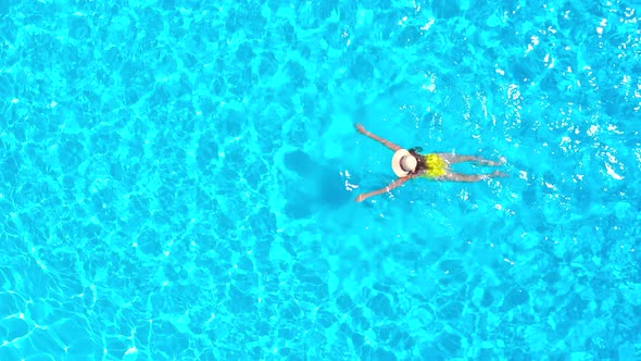 View From the Top As a Woman in Yellow Swimsuit Swims in the Pool